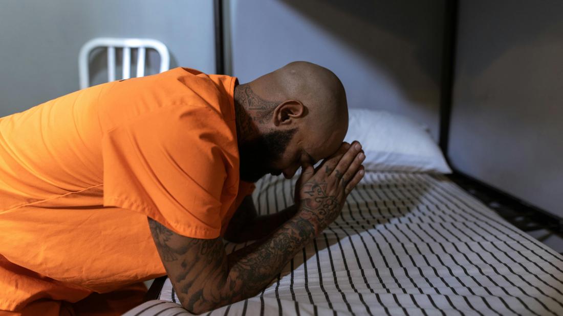 American Prisoner praying on a bed