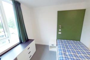 St Mary's standard single room with a bed, bed side cabinet and a desk